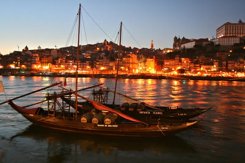 Rabelo boat on the Douro with Porto lit up in the evening